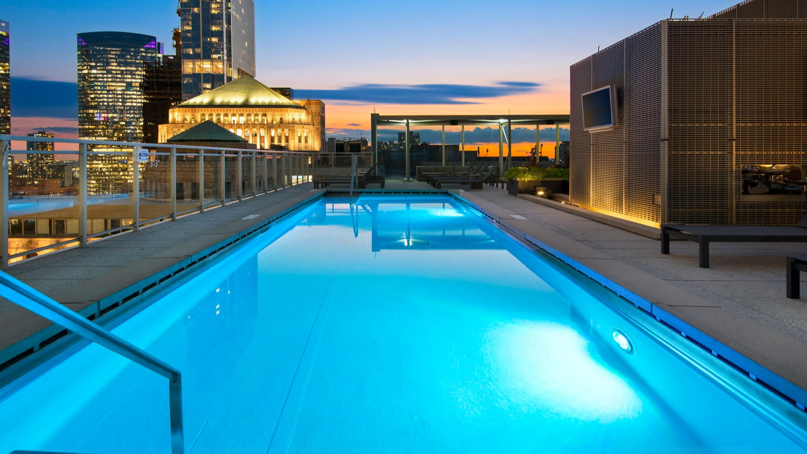Env Chicago rooftop pool with a panoramic city skyline view at dusk, showcasing urban luxury and serene water