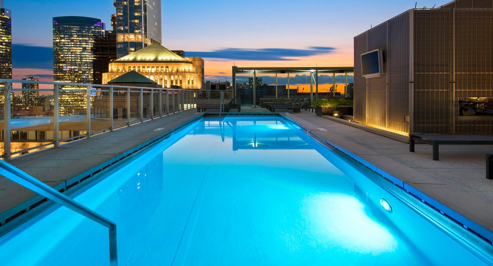 Env Chicago rooftop pool with a panoramic city skyline view at dusk, showcasing urban luxury and serene water