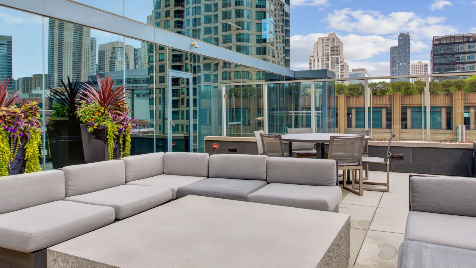 Env Chicago rooftop seating area with contemporary outdoor sofas and lush planters against a city backdrop