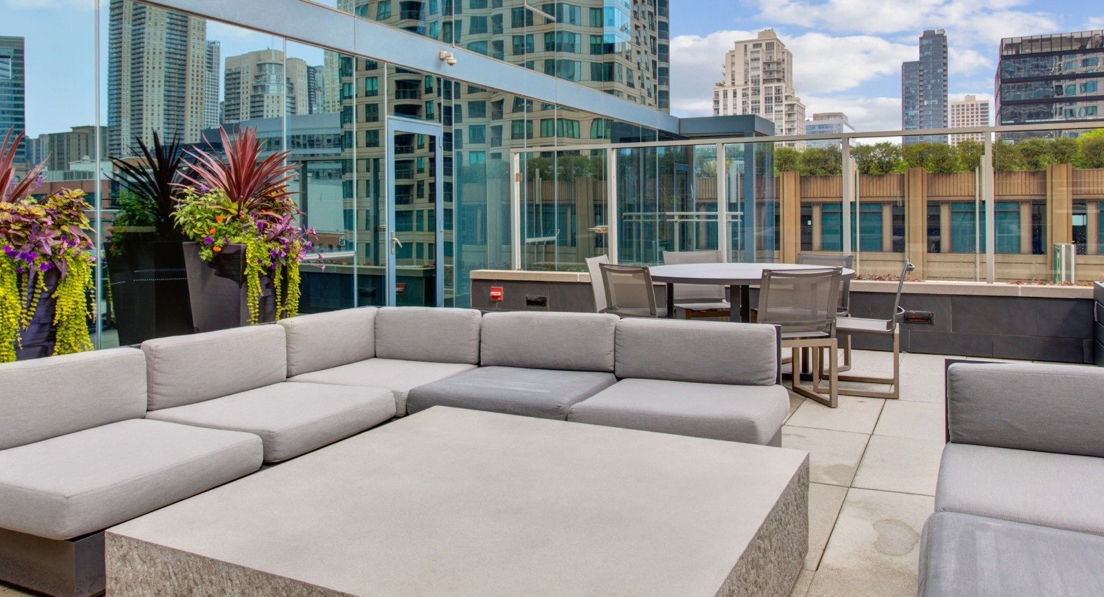 Env Chicago rooftop seating area with contemporary outdoor sofas and lush planters against a city backdrop