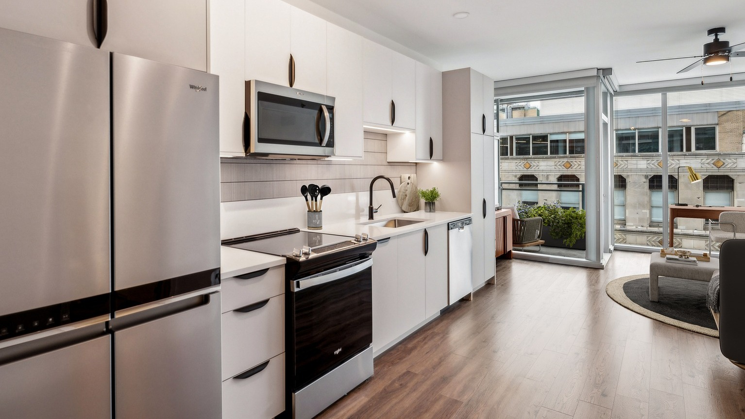 Sleek kitchen in an Env Chicago apartment, featuring stainless steel appliances and a vibrant city view from the window