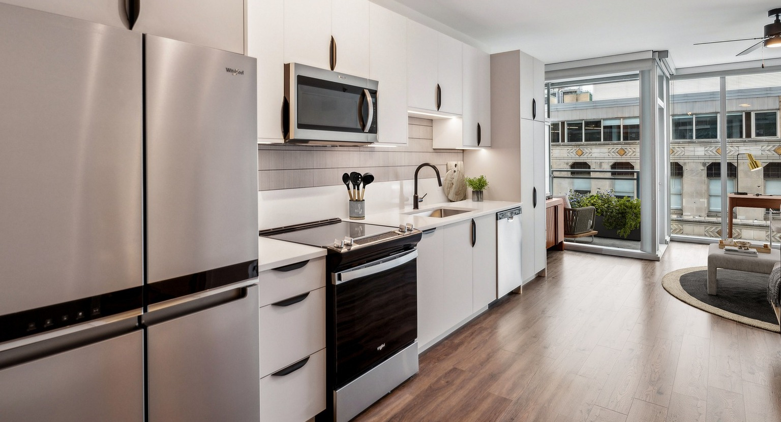 Sleek kitchen in an Env Chicago apartment, featuring stainless steel appliances and a vibrant city view from the window