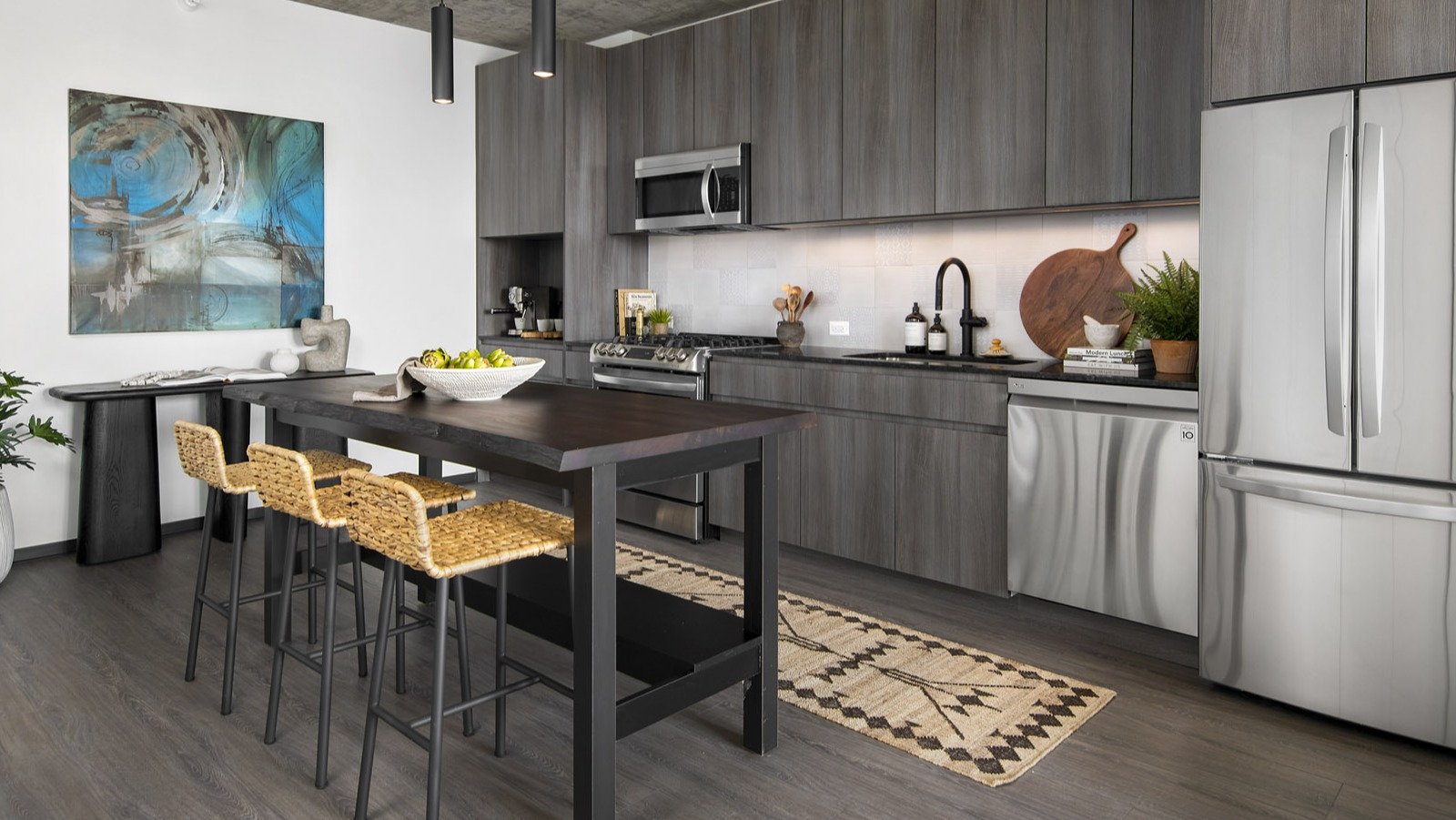 Contemporary apartment kitchen at Evo Union Park in Chicago, featuring dark wood cabinetry, stainless steel appliances, and a central island with seating