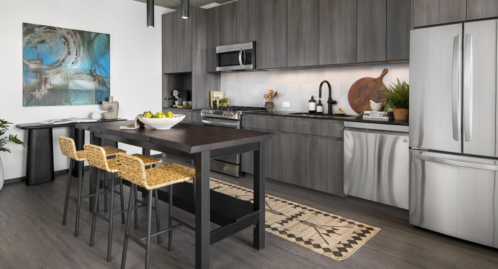 Contemporary apartment kitchen at Evo Union Park in Chicago, featuring dark wood cabinetry, stainless steel appliances, and a central island with seating