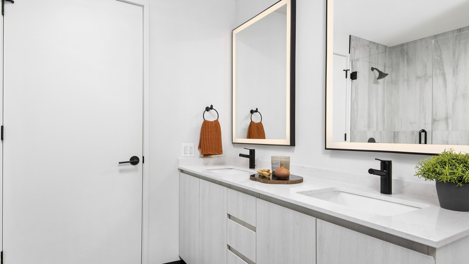 Bright and modern apartment bathroom at Evo Union Park in Chicago, featuring a double vanity, illuminated mirrors, and a spacious walk-in shower