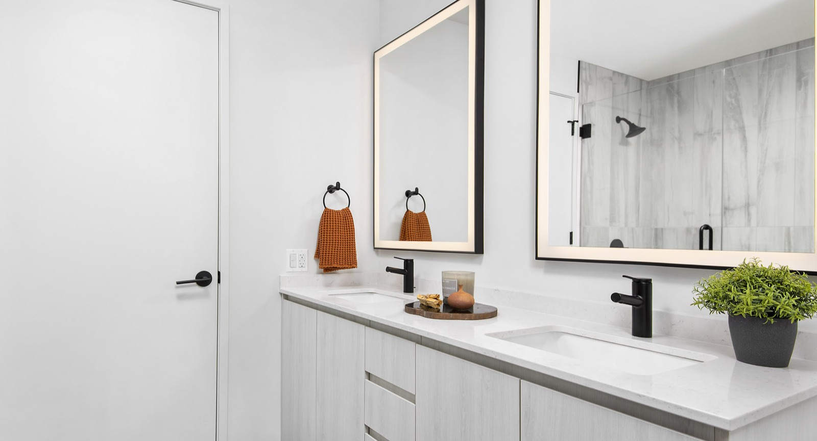 Bright and modern apartment bathroom at Evo Union Park in Chicago, featuring a double vanity, illuminated mirrors, and a spacious walk-in shower