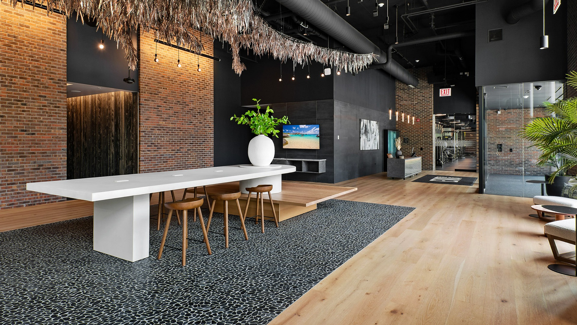 Stylish co-working lounge and lobby area at Evo Union Park in Chicago, featuring a large communal table, modern seating, and exposed brick