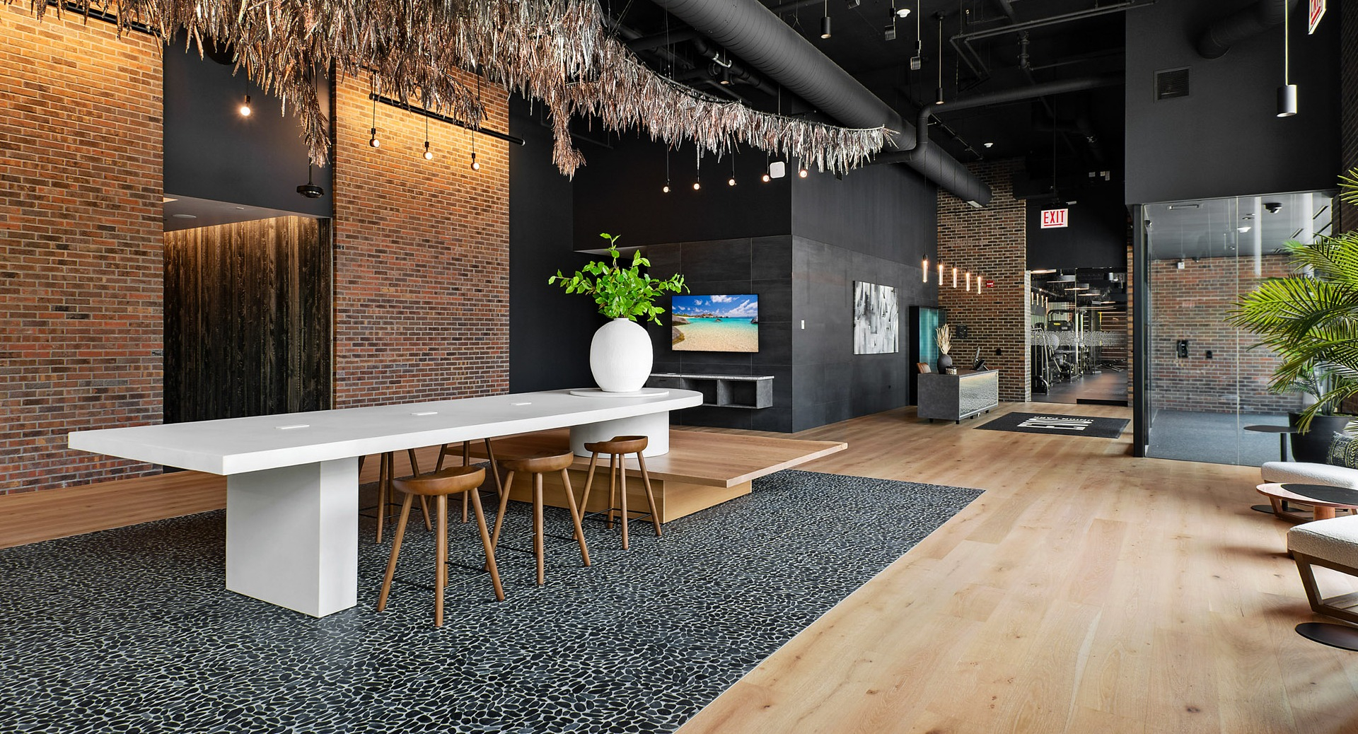 Stylish co-working lounge and lobby area at Evo Union Park in Chicago, featuring a large communal table, modern seating, and exposed brick