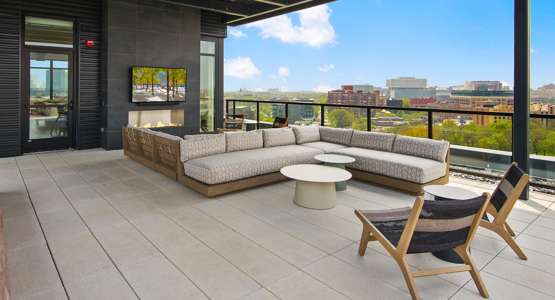 Covered outdoor lounge area on the rooftop at Evo Union Park in Chicago, with a large sectional sofa, fireplace, and flat-screen TV