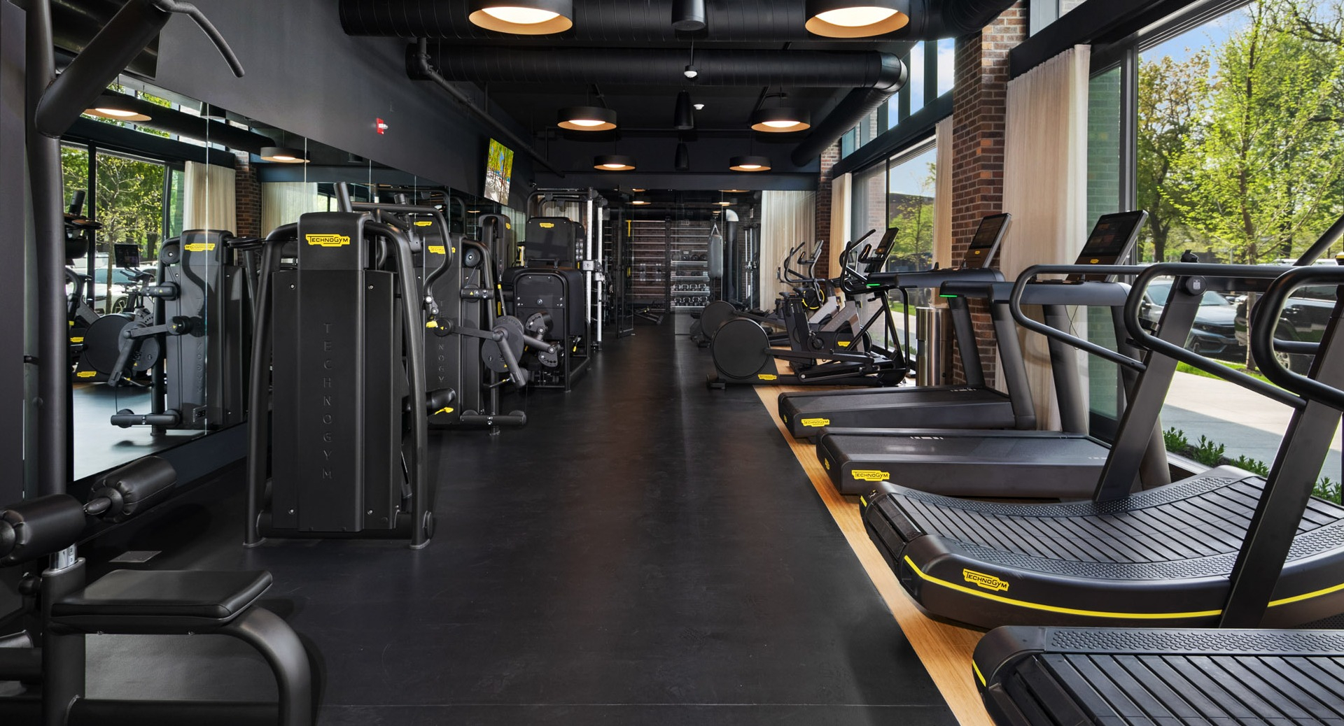 State-of-the-art cardio machines and strength equipment at Evo Union Park's gym in Chicago, with large windows overlooking greenery