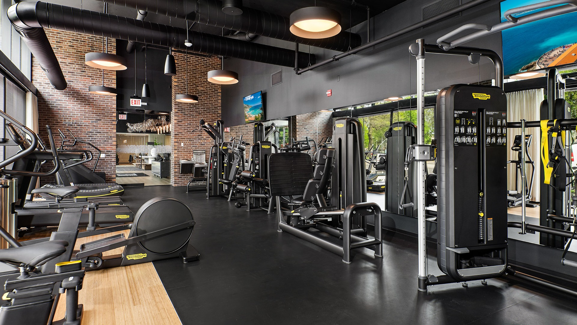 Expansive fitness center at Evo Union Park in Chicago, with a wide array of strength training machines, mirrors, and brick accents