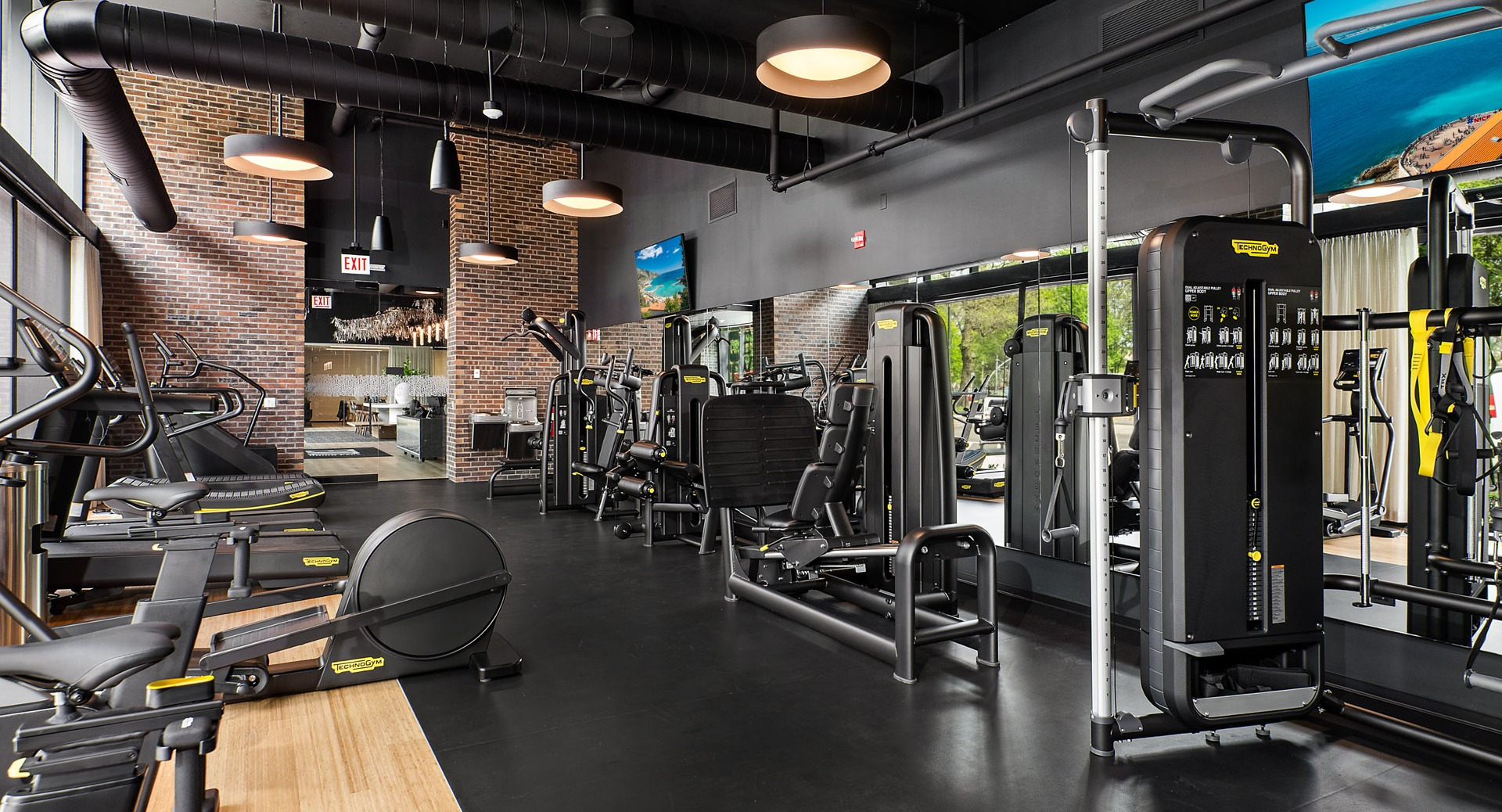 Expansive fitness center at Evo Union Park in Chicago, with a wide array of strength training machines, mirrors, and brick accents
