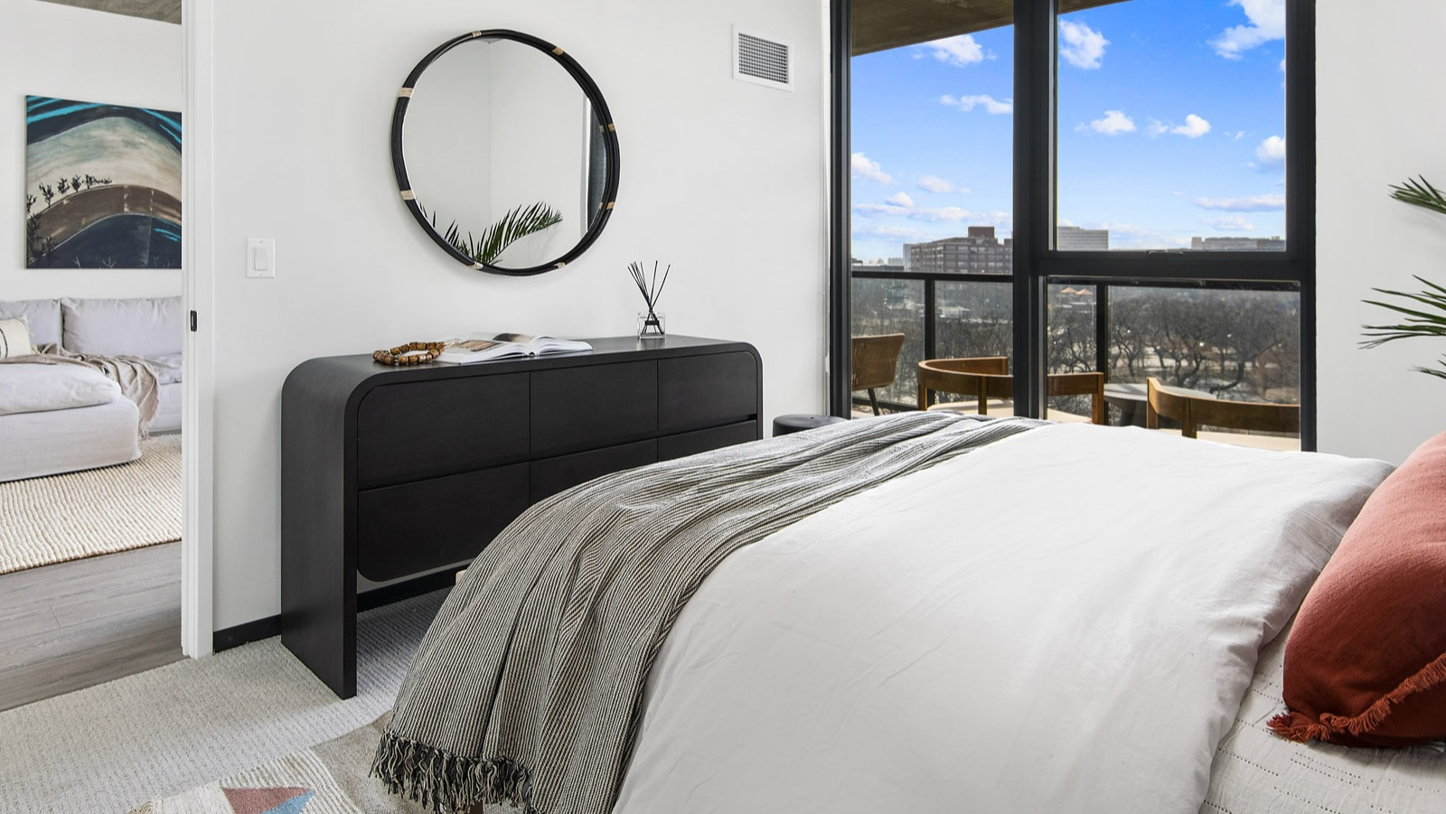 Modern apartment bedroom at Evo Union Park in Chicago, with a comfortable bed, sleek dresser, and large windows bringing in natural light and views