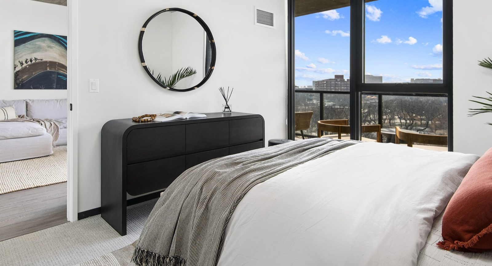 Modern apartment bedroom at Evo Union Park in Chicago, with a comfortable bed, sleek dresser, and large windows bringing in natural light and views