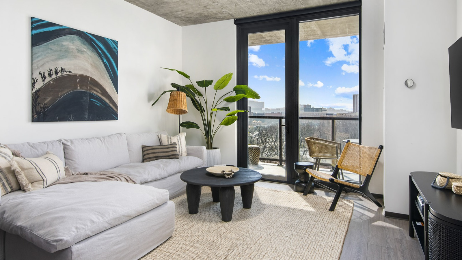 Modern apartment living room at Evo Union Park in Chicago, with a large sectional sofa, stylish decor, and access to a private balcony
