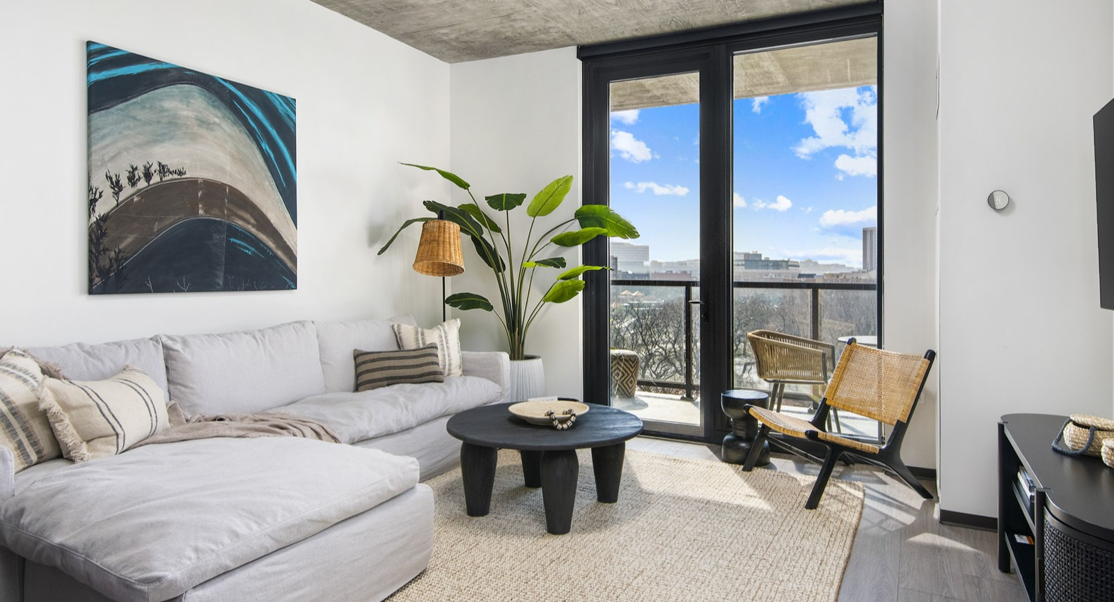 Modern apartment living room at Evo Union Park in Chicago, with a large sectional sofa, stylish decor, and access to a private balcony