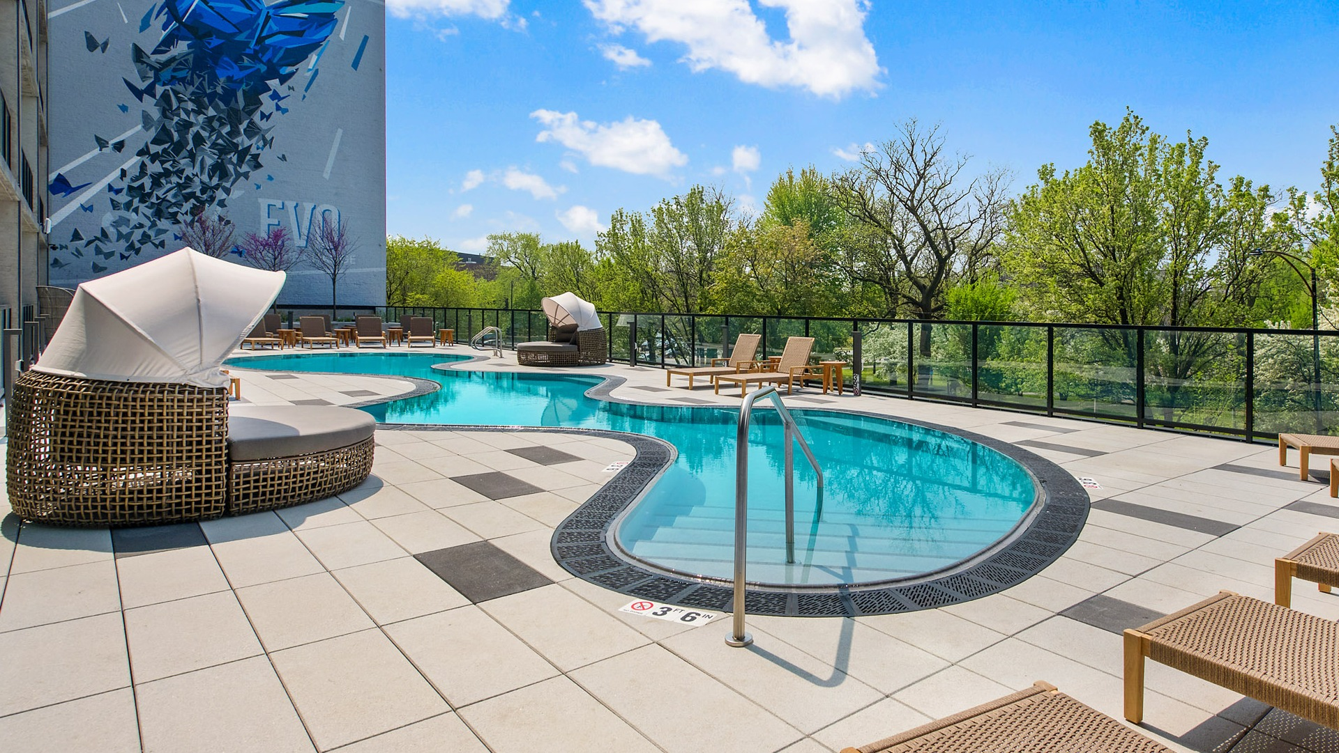 Resort-style outdoor swimming pool and sun deck at Evo Union Park in Chicago, with lounge chairs and artistic building murals