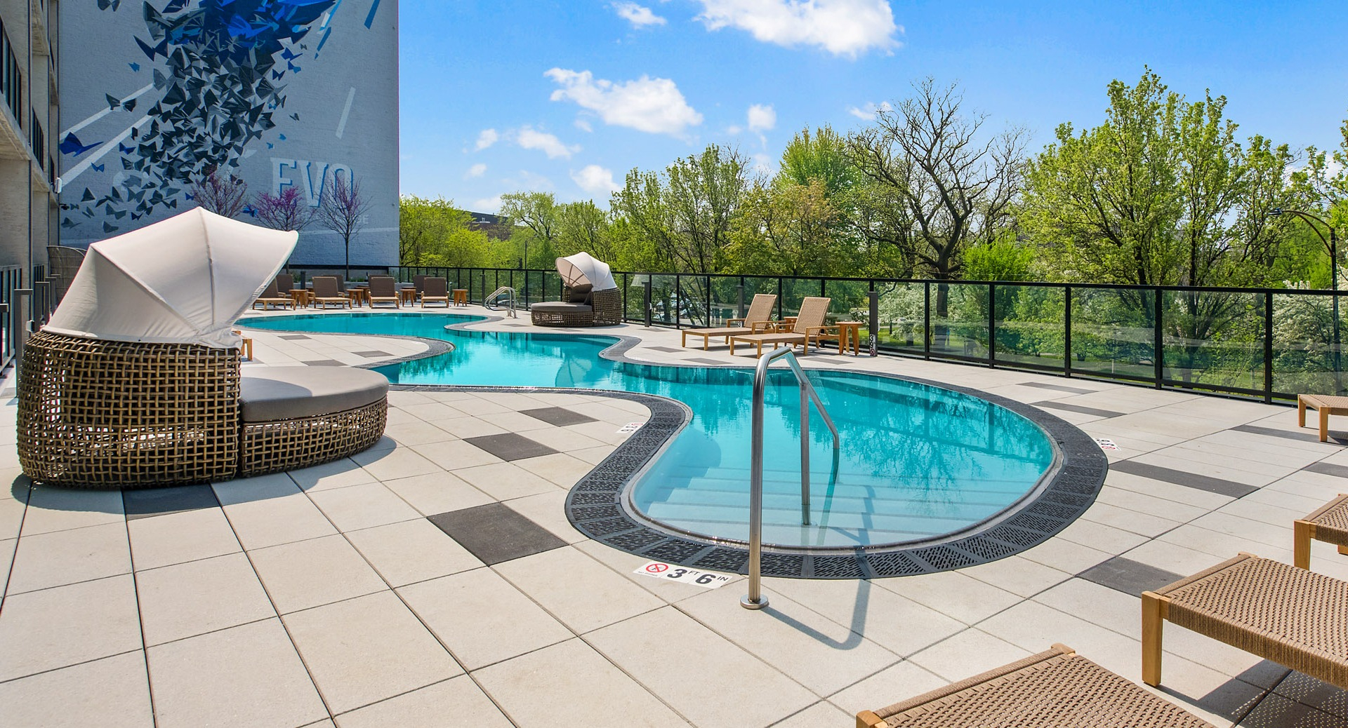 Resort-style outdoor swimming pool and sun deck at Evo Union Park in Chicago, with lounge chairs and artistic building murals