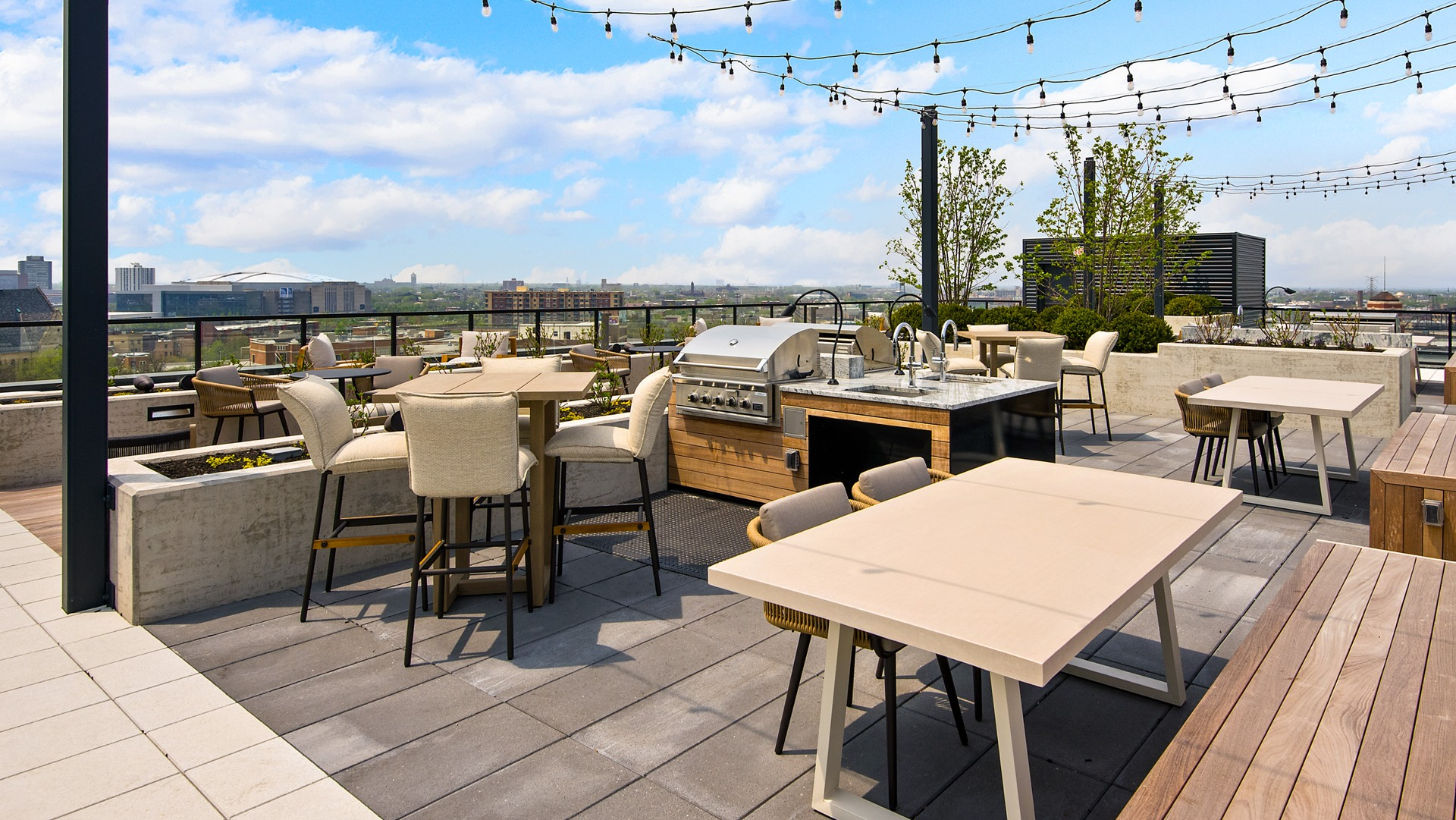 Spacious rooftop deck at Evo Union Park in Chicago, featuring an outdoor grilling station, dining tables, and string lights for entertaining