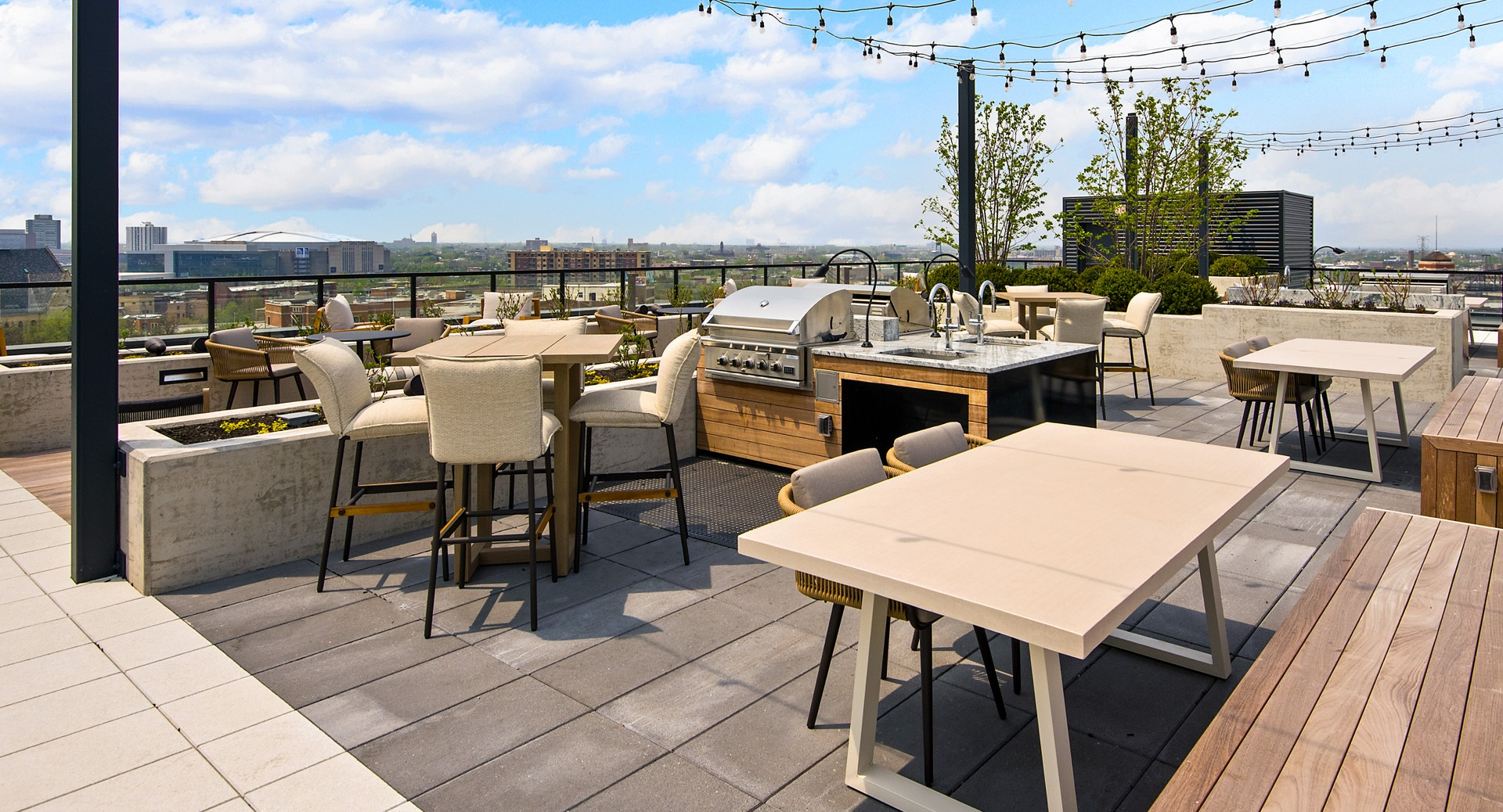 Spacious rooftop deck at Evo Union Park in Chicago, featuring an outdoor grilling station, dining tables, and string lights for entertaining