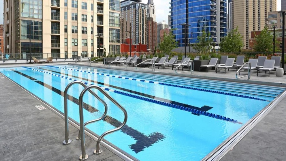 Expansive outdoor lap pool with clear blue water and city building views in the background at Exhibit on Superior in Chicago