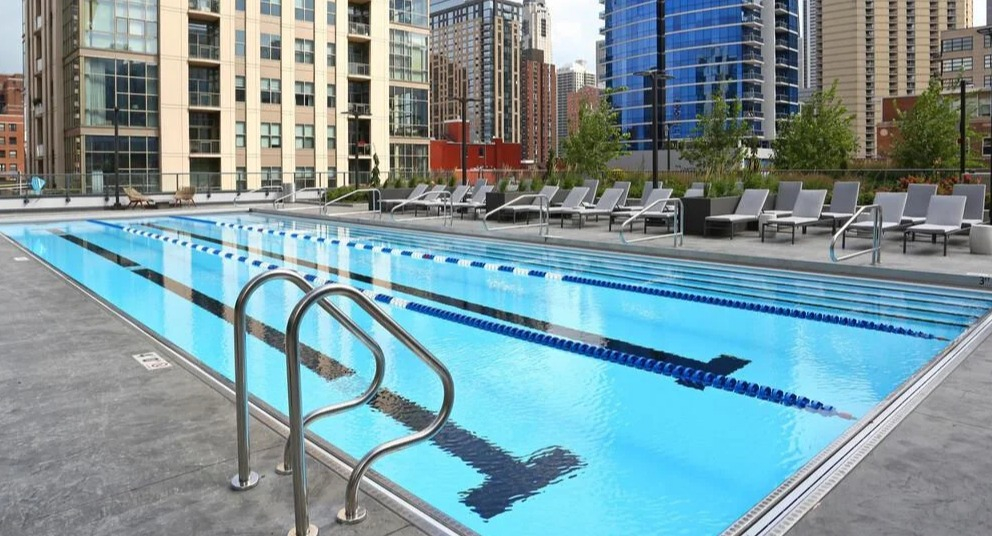 Expansive outdoor lap pool with clear blue water and city building views in the background at Exhibit on Superior in Chicago