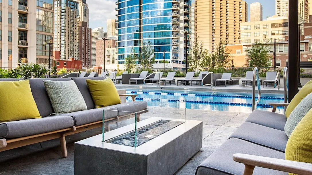 Stunning outdoor pool area with comfortable lounge seating, a fire pit, and urban skyline views at Exhibit on Superior in Chicago