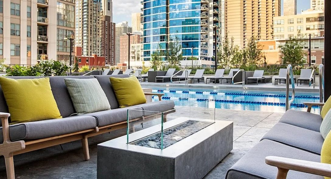 Stunning outdoor pool area with comfortable lounge seating, a fire pit, and urban skyline views at Exhibit on Superior in Chicago