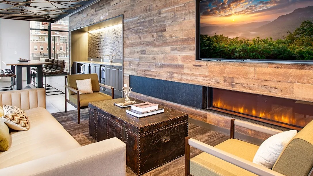 Luxurious resident lounge with a modern fireplace, TV, comfortable seating, and a wet bar area at Exhibit on Superior in Chicago