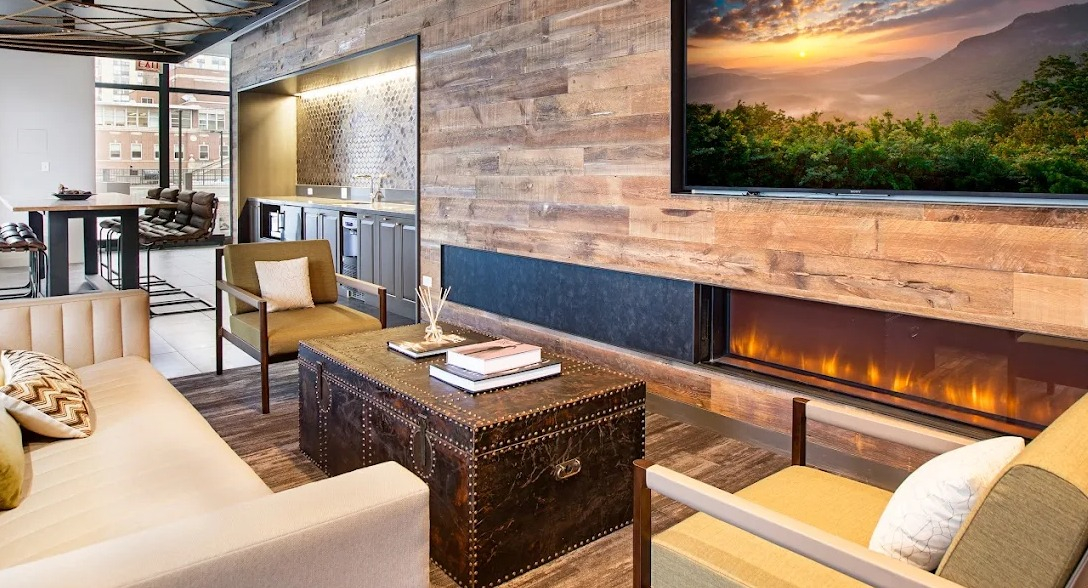 Luxurious resident lounge with a modern fireplace, TV, comfortable seating, and a wet bar area at Exhibit on Superior in Chicago