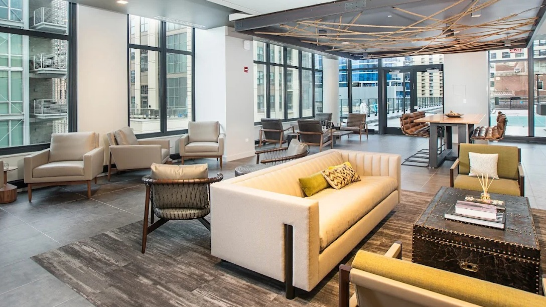 Spacious resident lounge with diverse seating, a large dining table, and access to an outdoor area at Exhibit on Superior in Chicago