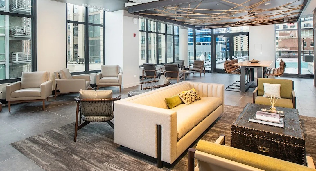 Spacious resident lounge with diverse seating, a large dining table, and access to an outdoor area at Exhibit on Superior in Chicago