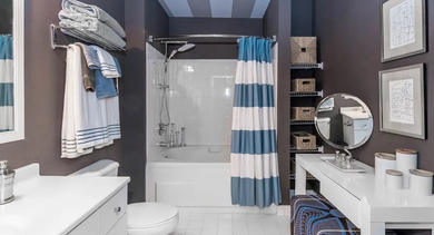 Stylish apartment bathroom at Fisher Building Apartments in Chicago, featuring a unique striped ceiling, modern vanity, and a shower-tub combo