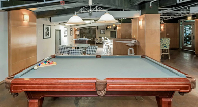 Entertainment-focused billiards room at Fisher Building Apartments in Chicago, featuring a classic pool table and stylish overhead lighting