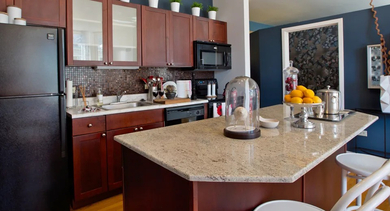 Modern apartment kitchen at Fisher Building Apartments in Chicago, with dark wood cabinetry, granite countertops, and a large island