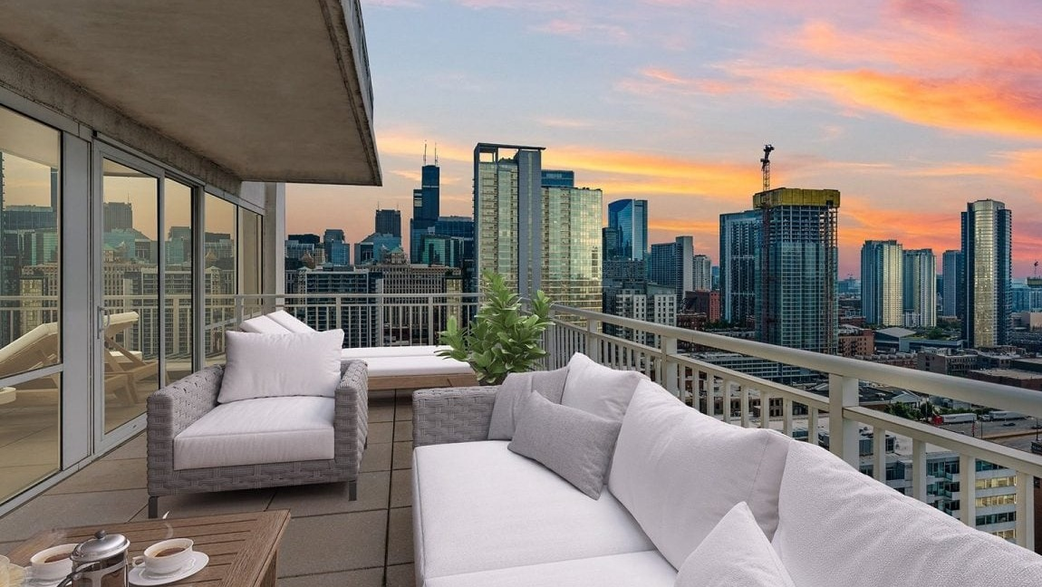 Expansive apartment balcony at Flair Tower Apartments in Chicago, offering breathtaking panoramic city views against a vibrant sunset sky