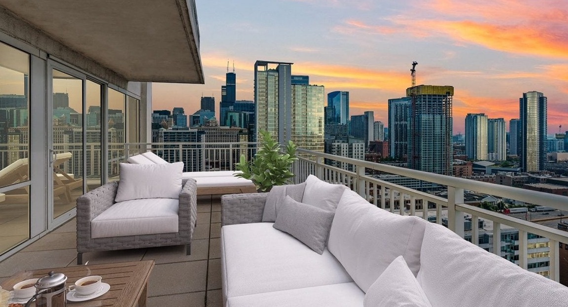 Expansive apartment balcony at Flair Tower Apartments in Chicago, offering breathtaking panoramic city views against a vibrant sunset sky