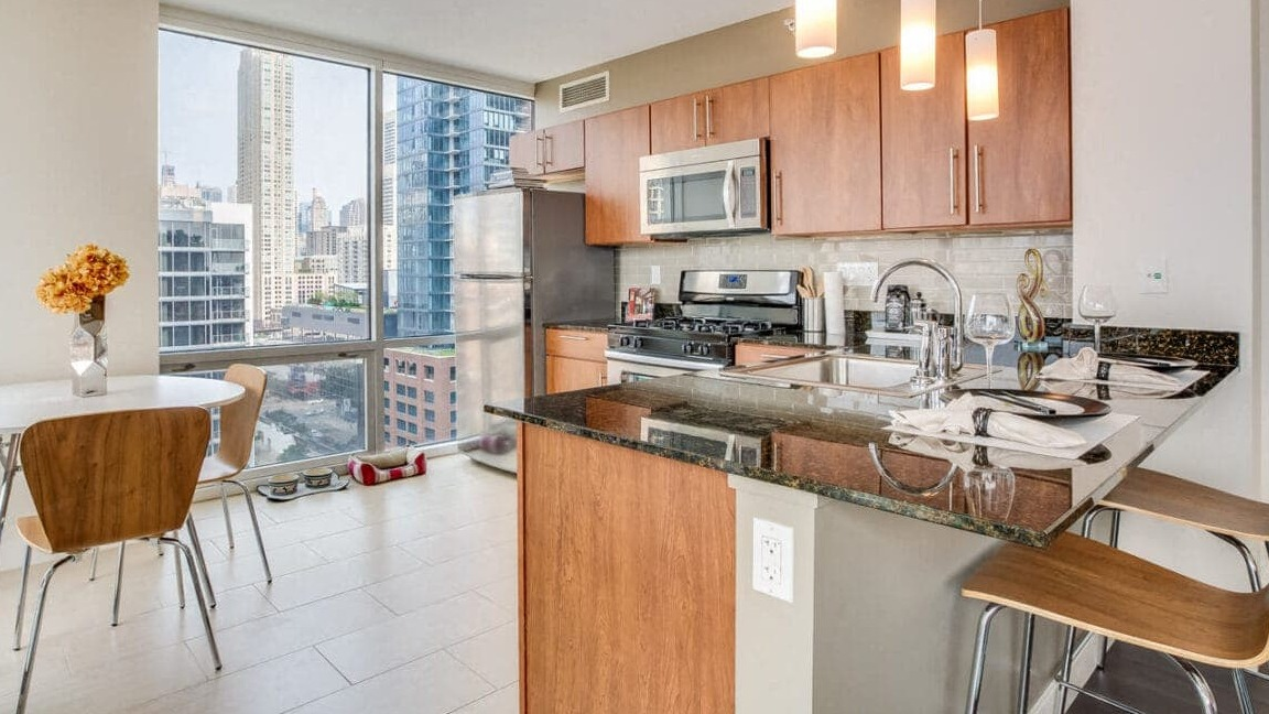 Bright apartment kitchen and dining nook at Flair Tower Apartments in Chicago, featuring city views and modern appliances