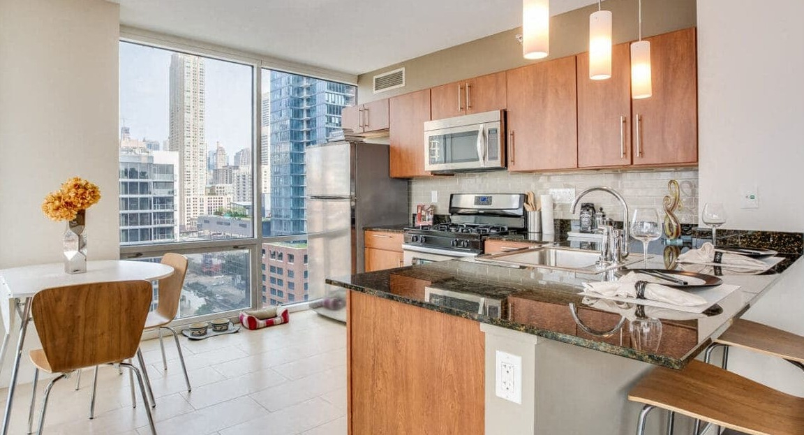 Bright apartment kitchen and dining nook at Flair Tower Apartments in Chicago, featuring city views and modern appliances