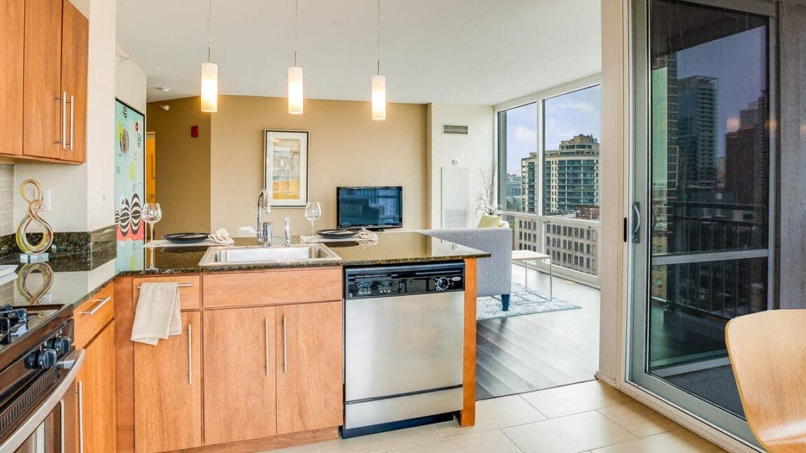 Modern apartment kitchen and living area at Flair Tower Apartments in Chicago, opening to a balcony with city views