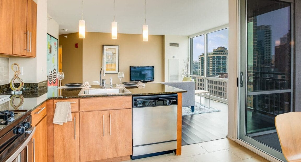 Modern apartment kitchen and living area at Flair Tower Apartments in Chicago, opening to a balcony with city views