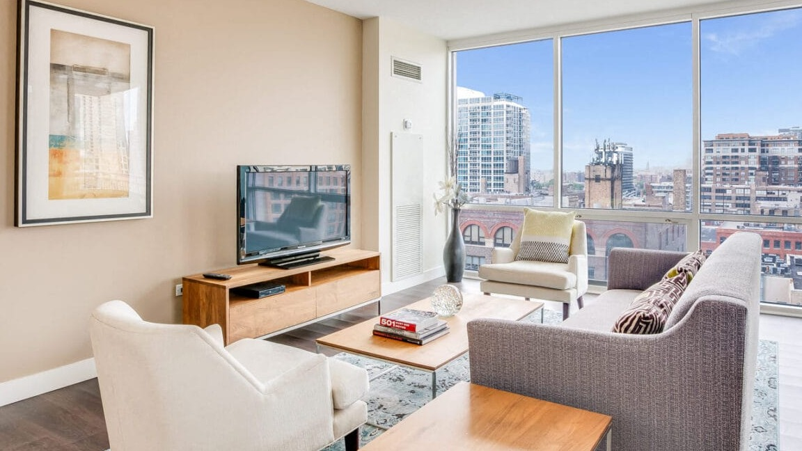 Bright apartment living room at Flair Tower Apartments in Chicago, offering expansive city views through large windows and comfortable seating