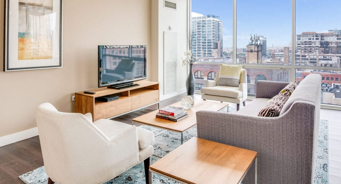 Bright apartment living room at Flair Tower Apartments in Chicago, offering expansive city views through large windows and comfortable seating