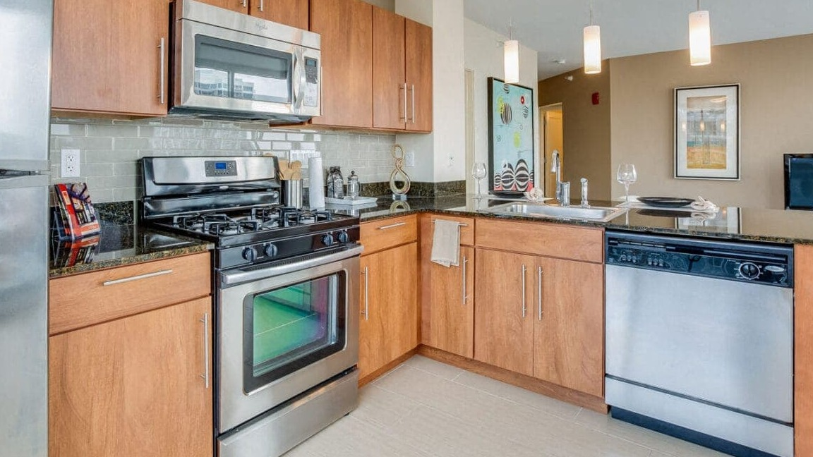 Modern apartment kitchen at Flair Tower Apartments in Chicago, with wood cabinetry, stainless steel appliances, and sleek design