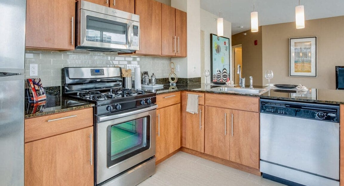 Modern apartment kitchen at Flair Tower Apartments in Chicago, with wood cabinetry, stainless steel appliances, and sleek design