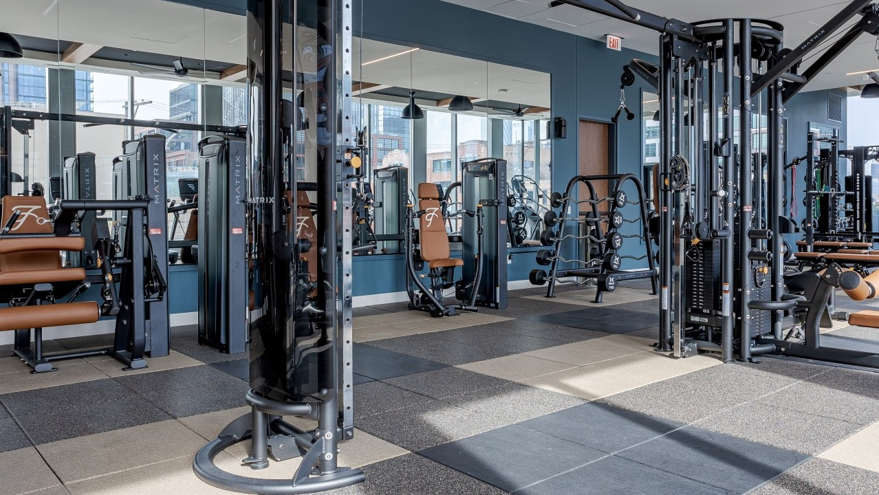 Expansive fitness center at Flora apartments in Chicago, offering a wide range of strength and cardio machines in a bright space