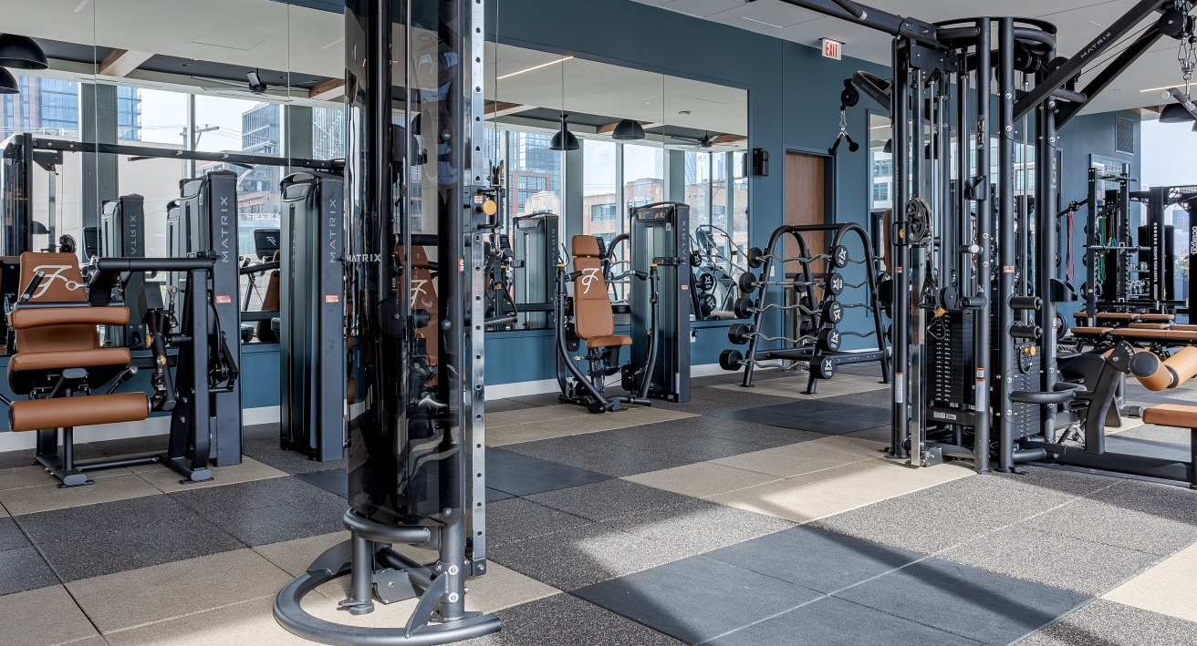 Expansive fitness center at Flora apartments in Chicago, offering a wide range of strength and cardio machines in a bright space