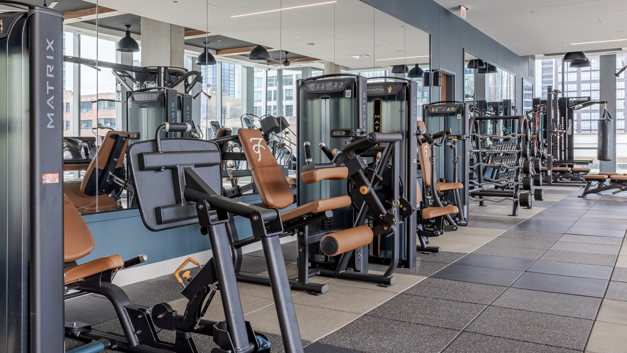 Modern gym at Flora apartments in Chicago, equipped with various strength training machines and mirrors, perfect for a full workout