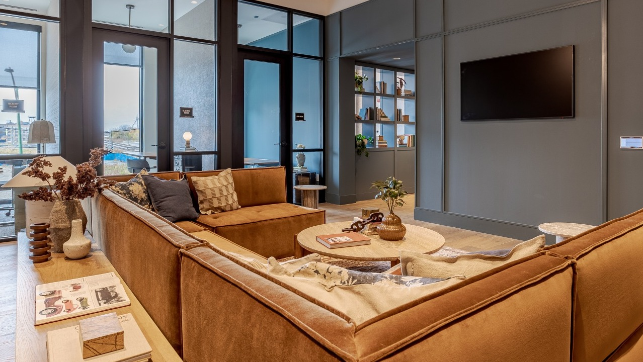 Inviting lobby lounge at Flora apartments in Chicago, with comfortable brown sofas, stylish decor, and a welcoming atmosphere