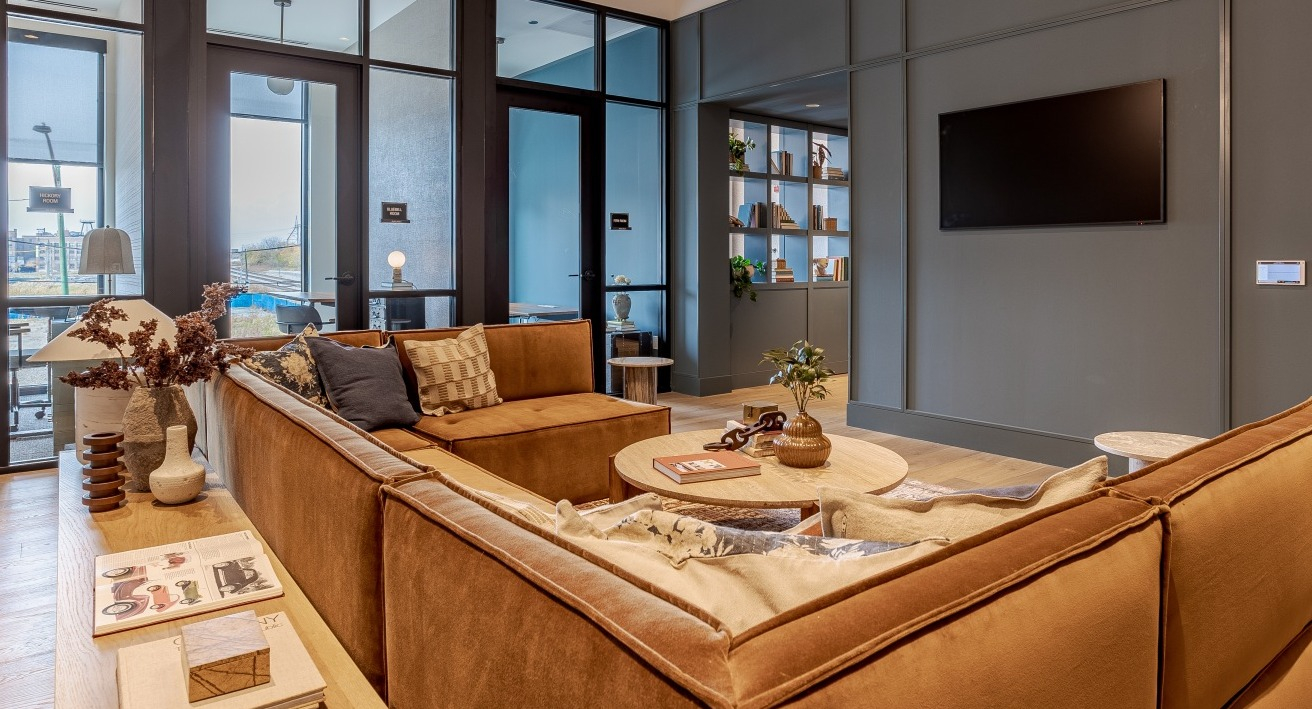 Inviting lobby lounge at Flora apartments in Chicago, with comfortable brown sofas, stylish decor, and a welcoming atmosphere